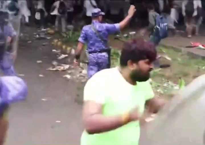 Man confronts riot police behind a raised shield