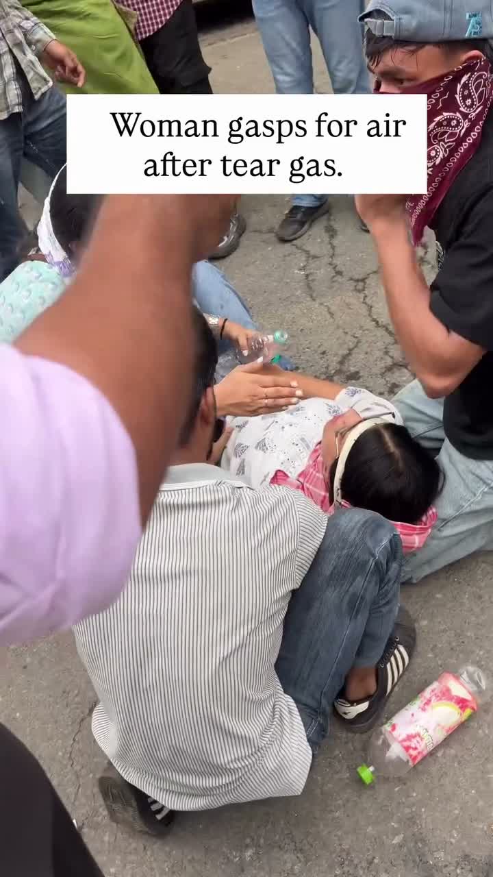 Woman lies on the ground surrounded by people trying to help her