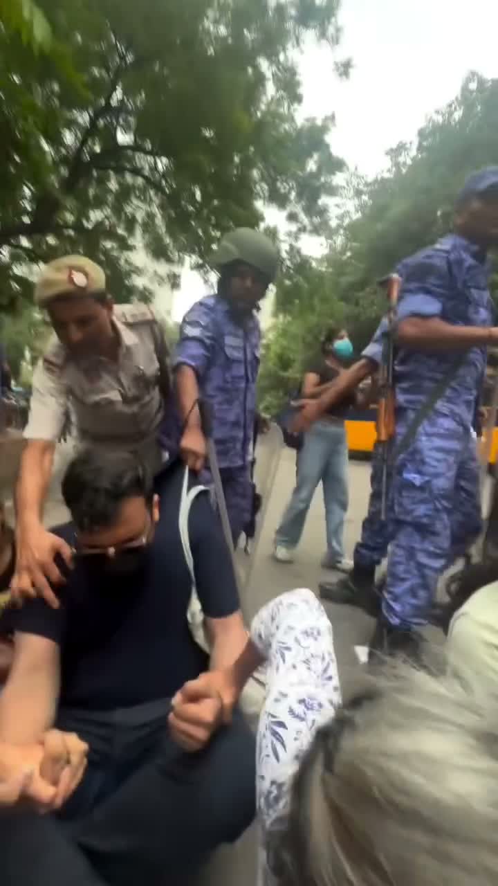 Paramilitary personnel pull a woman near a bus as others try to hold her back