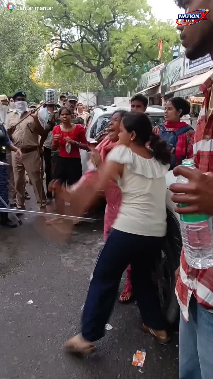 Crowd gestures near parked cars at Jantar Mantar