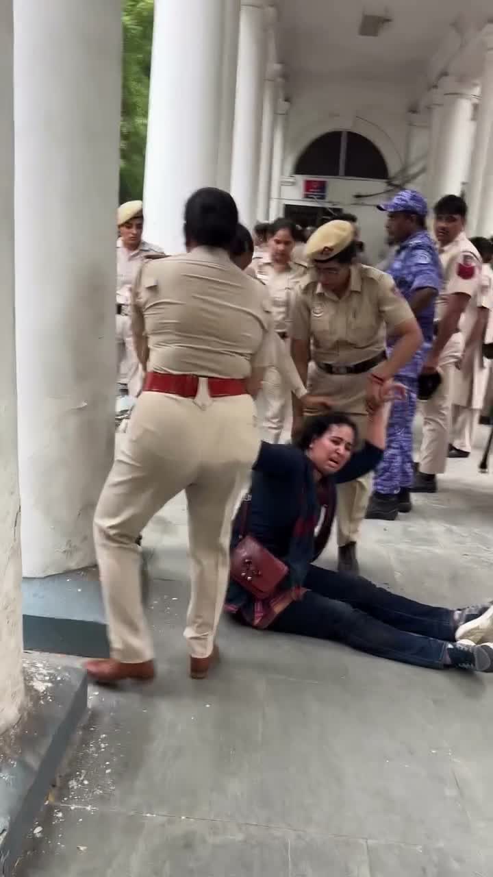 Police officers surround a person lying on the pavement