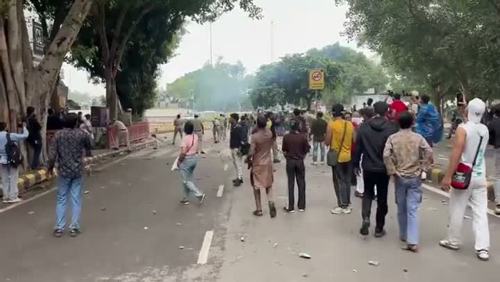 Police line a debris-strewn street as smoke rises